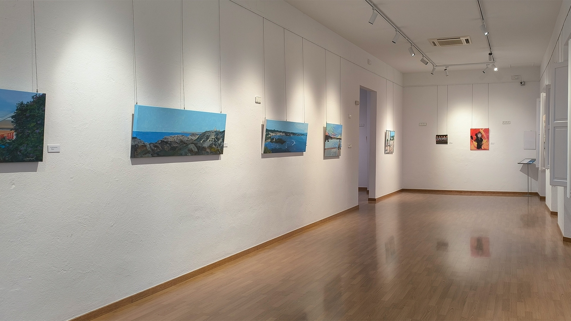 Vista de la sala gran de l’exposició MOMENTS, amb una seqüència d’obres en acrílic sobre tela a la paret esquerra i la continuïtat del recorregut cap a la sala del fons.