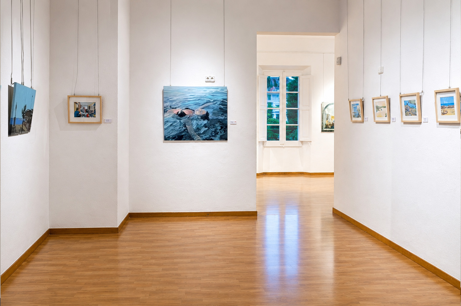 Vista de la sala mitjana de l’exposició MOMENTS, amb aquarel·les de petit format i obres en acrílic sobre tela de format més gran, marcant el pas cap a la sala següent del recorregut.